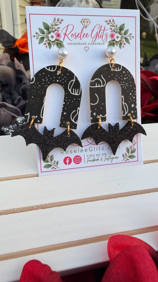 Roselee Glitz handmade dangle earrings featuring black arch pieces with celestial cat motifs and glittery bat charms.
