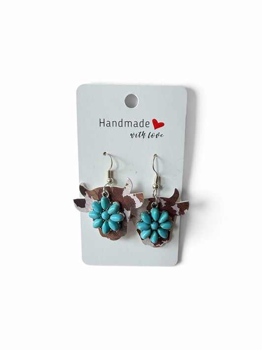 Roselee Glitz cow-shaped dangle earrings with brown and white cow print and turquoise floral accents on a display card.