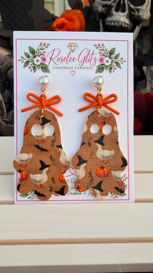Roselee Glitz ghost-shaped faux leather dangle earrings featuring witch-hat ducks, pumpkins, and orange bows.