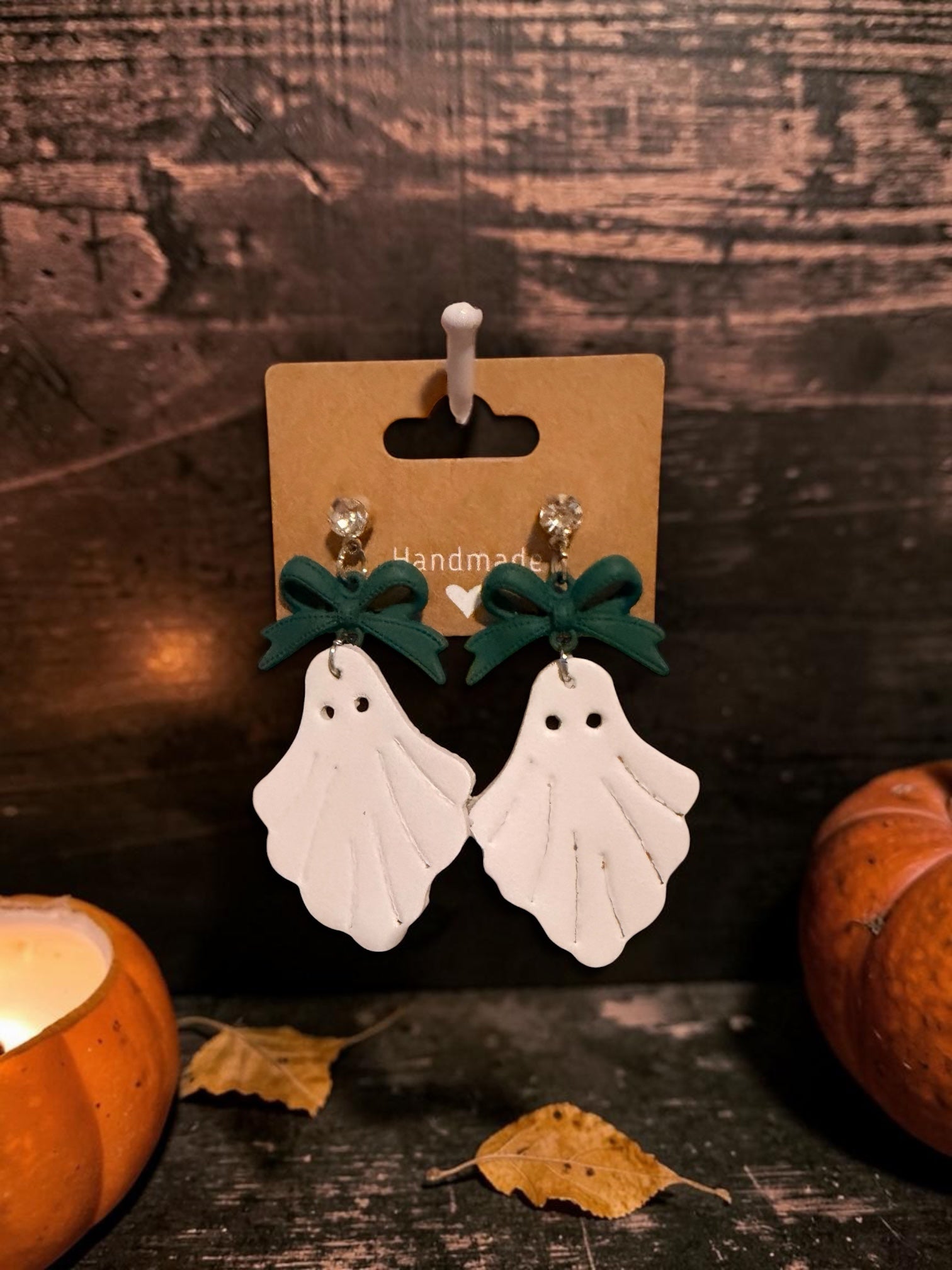 Roselee Glitz handmade white ghost dangle earrings with dark green bows and crystal studs on a display card.