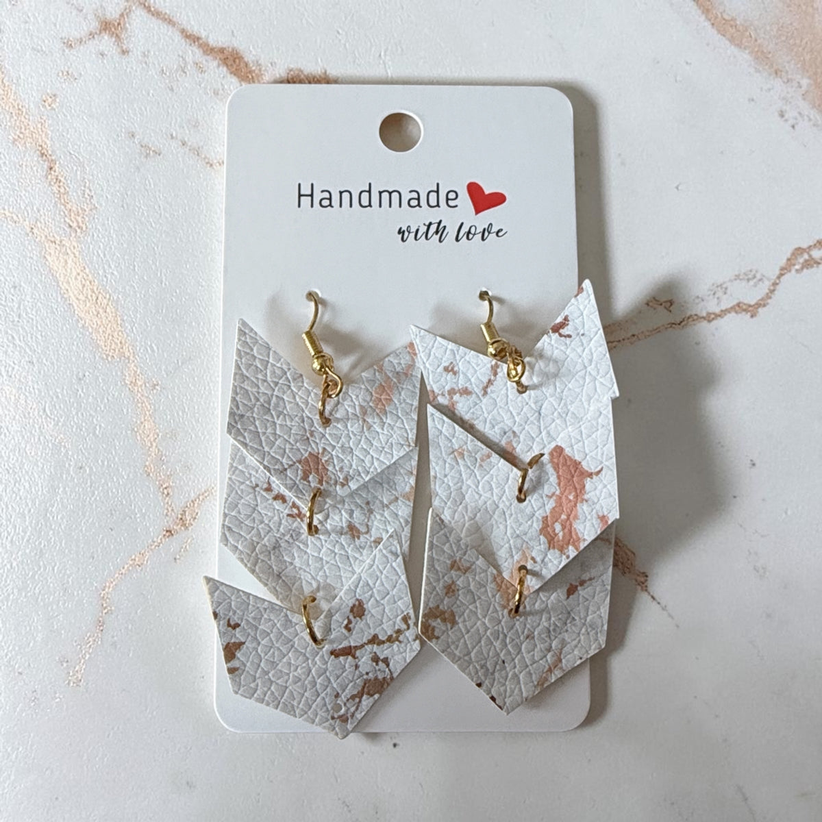 Roselee Glitz layered arrow drop earrings in white faux leather with rose gold metallic marble pattern and gold hooks.