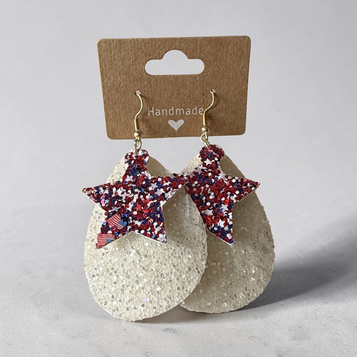 Roselee Glitz handmade teardrop earrings with white glitter base and red, white, and blue star accents on hooks.