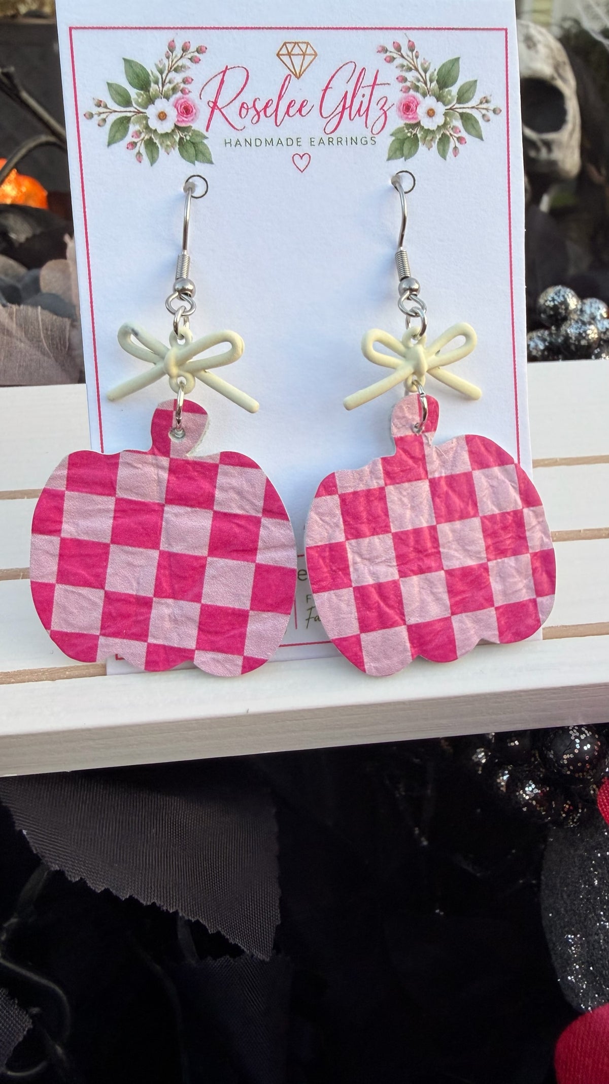 Roselee Glitz pink and light pink checkered pumpkin dangle earrings with small cream bows on a display card.