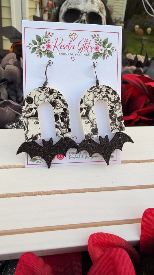 Roselee Glitz handmade arch earrings featuring a monochromatic skull print and shimmering black glitter bat silhouettes.