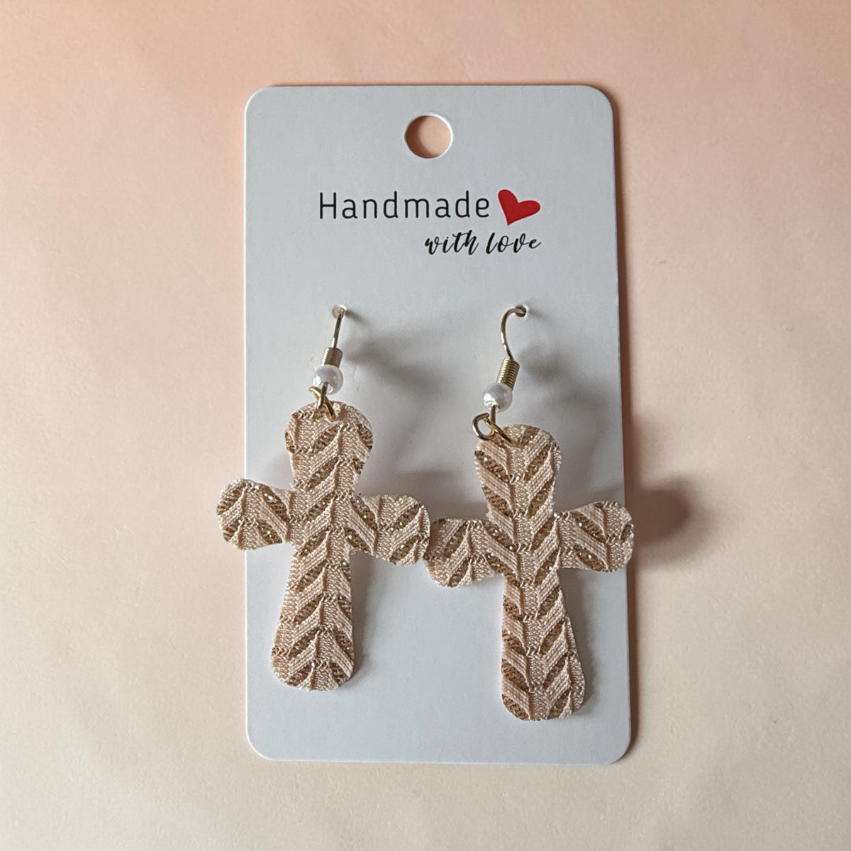 Roselee Glitz gold-tone textured cross dangle earrings with a herringbone pattern on a handmade display card.