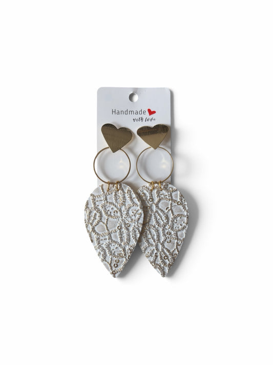 Roselee Glitz white faux leather teardrop earrings with gold lace embossing, heart studs, and gold hoops on display.
